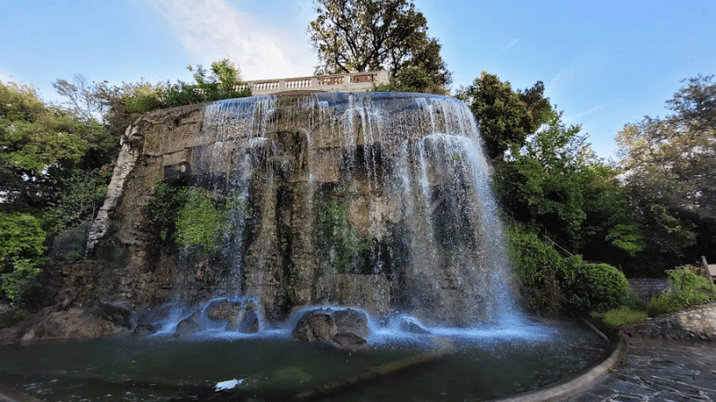 cascade artificielle dans un parc avec vue sur la ville et la mer