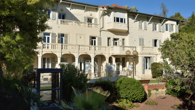 Façade d'un bâtiment haussmannien blanc avec balcon. Conservatoire de Cannes