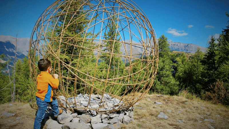 un enfant devant une sculpture au Sentier Planétaire de Valberg - Randonnée astronomie en famille